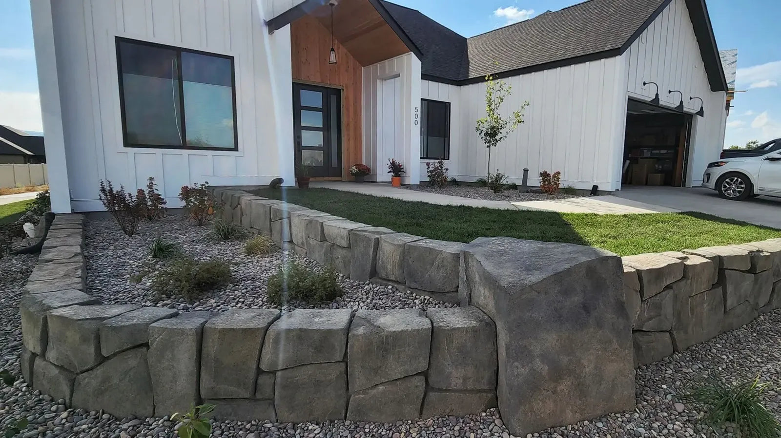 Carved concrete garden wall in front of a modern farmhouse